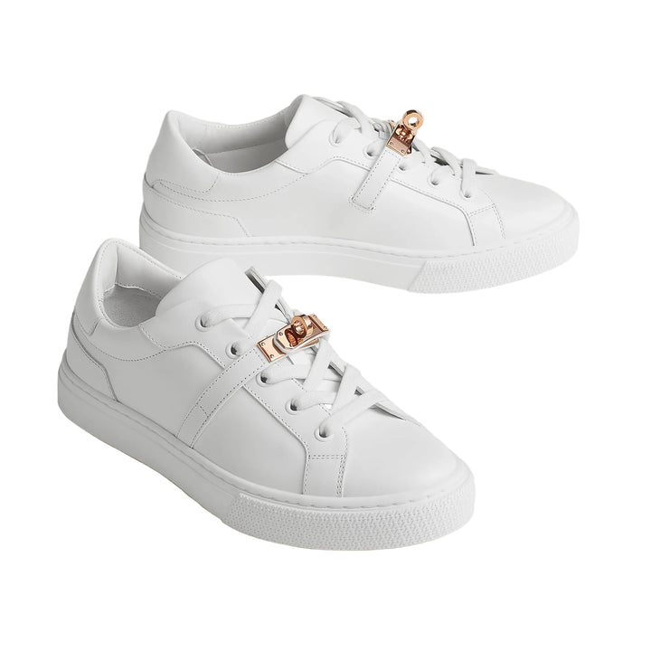 hermes day sneaker White sneakers with rose gold accents on a light beige background
